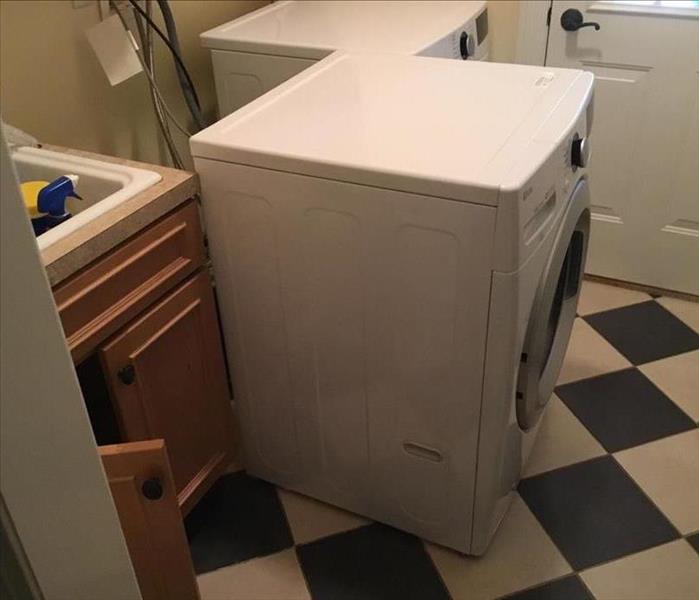 Washing Machine in a basement with wet floor underneath from leak